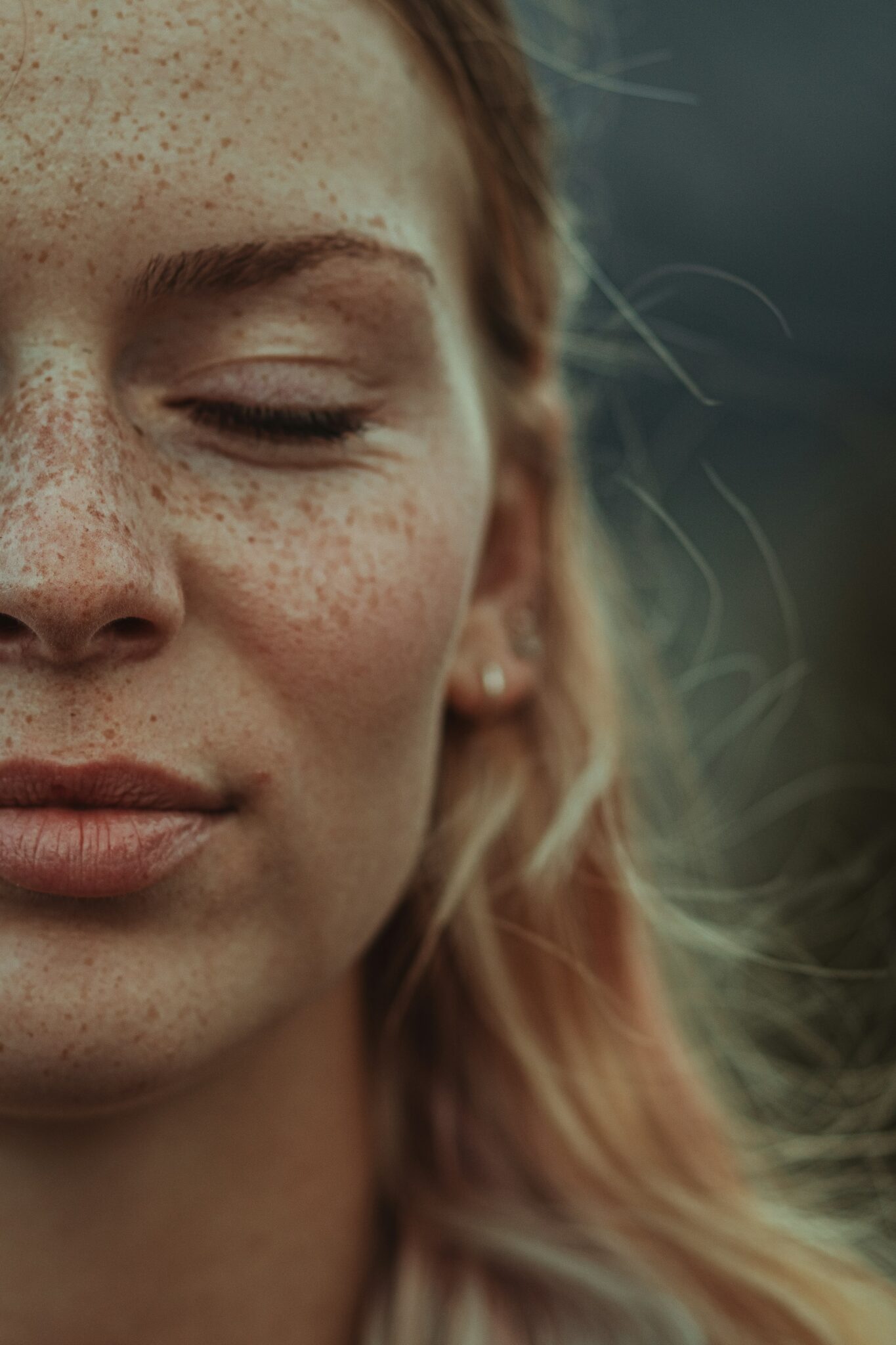 Picture of a woman's face with freckles and eyes shut.